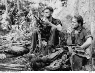 MOROKAIMORO, BOUGAINVILLE, 1945-06-12. TPR T.E. YATES (1) AND L-CPL G.W. WELLS (2), MEMBERS OF 2/8 COMMANDO SQUADRON, EATING FRESH APPLES WHICH HAVE BEEN DROPPED BY AIR. THE MEN HAVE JUST RETURNED ..