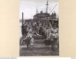 LAE, NEW GUINEA, 1945-05-07. AUSTRALIAN WOMEN'S ARMY SERVICE PERSONNEL DISEMBARKING FROM A LANDING BARGE AT MILFORD HAVEN. THE MV DUNTROON WHICH BROUGHT THEM FROM AUSTRALIA IS IN THE BACKGROUND. ..