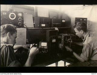 Lae, New Guinea. 1944-06-18. Signalman C. Moore (left) and Signalman F. Kieck are two members of 17 Technical Maintenance Section overhauling and checking an AT5-ARS (Type 112) wireless transmitter ..