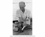 Kelshaw Bonham taking radiation readings from a crab aboard ship, Bikini Atoll, summer 1964