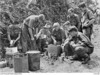 Finschhafen Area, New Guinea. c. 1943-12. An Australian Comforts Fund representative handing out food packs to some Australian soldiers