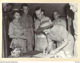 BOUGAINVILLE. 1945-09-29. DRIVER T. WILSON (2) WATCHES HIS BRIDE PRIVATE M. WILSON, AUSTRALIAN ARMY MEDICAL WOMEN'S SERVICE (1) SIGN THE MARRIAGE CERTIFICATE AFTER THEIR WEDDING AT 2/1 GENERAL ..