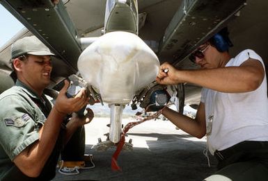 SSGT Darrell J. Bucy, left, and A1C Scott Catino, right, load Bomb Disposal Unit bombs onto an F-4 Phantom II aircraft. The airmen are assigned to the 3rd Munitions Maintenance Squadron, involved in Exercise Opportune Journey 4