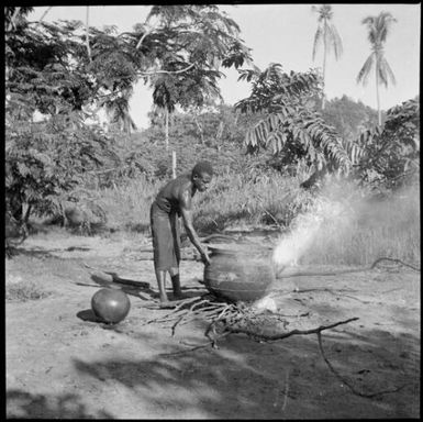 Aiau, the Chinnery's garden boy, tending a cooking pot, Malaguna Road, Rabaul, New Guinea, ca. 1936 / Sarah Chinnery