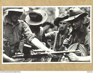 MOUNT PROTHERO AREA, NEW GUINEA. 1944-01-21. PERSONNEL OF THE 2/2ND PIONEER BATTALION WHO HAVE JUST RETURNED FROM A PATROL OF THE CANNING SADDLE AREA EXAMINE A JAPANESE MACHINE GUN CAPTURED IN AN ..