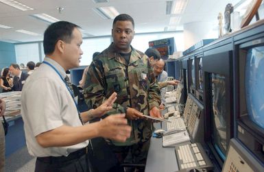 MASTER Sergeant (MSGT) Michael Williams, right, a search and rescue controller from the 502nd Air Operations Squadron (AOS), Hickam Air Force Base (AFB), Hawaii, listens to Mister Patrick Yam, a Hong Kong air traffic controller, discuss search and rescue procedures during the Search and Rescue Exercise (SAREX) 2002