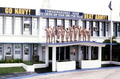 Alumni of the U.S. Naval Academy stationed on Guam show their support for the academy's football team prior to this year's Army/Navy games. (From L to R) LT. Mike Elton, Class of '89; LT. Bill Byrne, Class of '87; CDR. Jim Poole, Class of '76; LT. Keith Spencer, Class of '87; ENSIGN Tracy James, Class of '92; LT. Piper Spencer, Class of '89; Rear Admiral Edward E. Christensen, Commander U.S. Naval Forces, Marianas, Class of '65; Captain Charlie Young, CO of USS HOLLAND (AS-32), Class of '70; CDR. Brian Robertson, Class of '71; and LT. Gerald Peoples, Class of '84