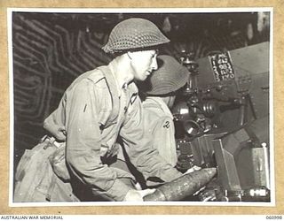 DONADABU AREA, NEW GUINEA. 1943-12-01. CREW MEMBERS OF A TROOPS, NO. 7 BATTERY, 2/4TH AUSTRALIAN FIELD REGIMENT LOADING THEIR 25-POUNDER FOR A NIGHT SHOOT. SHOWN ARE: VX21882 GUNNER E. N. CAVE (1); ..