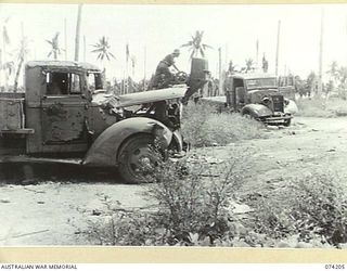 HANSA BAY, NEW GUINEA. 1944-06-22. NX86826 PRIVATE J.J. MAHONEY,4TH INFANTRY BATTALION, CHECKING OVER A CONCRETE MIXER AND TRUCKS ABANDONED BY THE JAPANESE FORCES WHEN THEY HURRIEDLY EVACUATED THE ..