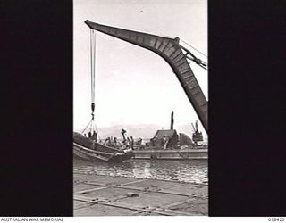 LAE, NEW GUINEA. 1943-10-13. LARGE FLOATING CRANE OF THE UNITED STATES SMALL SHIPS SECTION, RAISING A SUNKEN JAPANESE BARGE FROM THE DOCK AREA