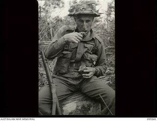 Donadabu, New Guinea. 1943-07-26. Q28641 Private N. J. Knight of the 61st Battalion eating bully beef and biscuits during a break in a supply dropping exercise