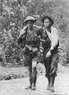 Walking wounded in the Sanananda area, possibly a  member of the 2/7th Cavalry Commando assisted by QX16184 Corporal A G 'Scrap Iron' Arthur
