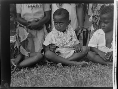 Unidentified young boy with a group of others at the meke, Vuda village, Fiji