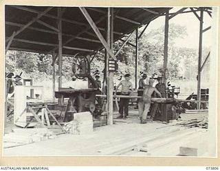 LAE, NEW GUINEA. 1944-06-09. A GENERAL VIEW OF THE WOOD MACHINE SHOP AT THE 2/7TH ADVANCED WORKSHOP. IDENTIFIED PERSONNEL ARE:- VX9803 SERGEANT H BALLINGER (1); WX9878 CRAFTSMAN A E SLATER (2); ..