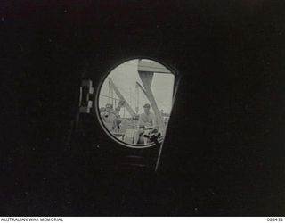 FINSCHHAFEN, NEW GUINEA. 1945-04-04. PRIVATE W. STRUDWICK, 2/48 INFANTRY BATTALION, (2), SEATED ON A WINCH AMIDSHIPS ABOARD THE VAN HEUTSZ ALONG SIDE PRIVATE C.A. OAKES, (1). THE MEN ARE VIEWED ..