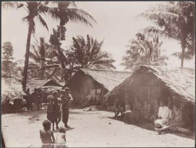 Villagers gathered in the shade of houses at Port Adam, Malaita, Solomon Islands, 1906 / J.W. Beattie