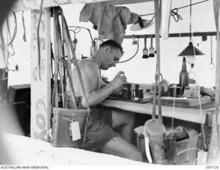 SEVENTEEN MILE, NEW GUINEA. 1943-09-23. VX33998 CORPORAL A. A. GALLAGHER OF THE 2/1ST AUSTRALIAN ARMY TOPOGRAPHICAL SURVEY COMPANY, AT WORK IN THE INSTRUMENT SECTION