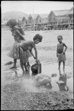 Woman filling a vessel from a tap, Hanuabada, Papua, ca. 1923 / Sarah Chinnery