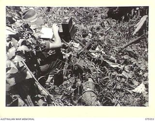 LAE, NEW GUINEA. 1945-03-11. A SIGNALLER OF THE NEW GUINEA SCHOOL OF SIGNALS OPERATING A WS208 MARK II SET UNDER WET AND MUDDY CONDITIONS