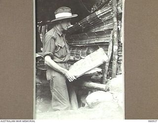 NEW GUINEA. 1943-11-28. W3421 LIEUTENANT COLONEL C. H. B. NORMAN DSO, MC, COMMANDING OFFICER, 2/28TH AUSTRALIAN INFANTRY BATTALION STUDYING A MAP OF THE FINNISCHAFFEN AREA BEFORE THE UNITS ADVANCE ..