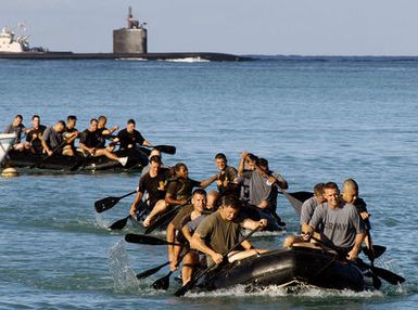 Three teams of service members from the Joint POW/MIA Accounting Command (JPAC) paddle their Zodiac rafts to the shore during Zodiac training at Hickam Harbor, Hickam Air Force Base (AFB), Hawaii (HI). The US Army (USA) 7th Engineer Detachment (Heavy Dive), Fort Shafter, HI, conducts the training for JPAC to increase the unit's readiness for water recovery missions. JPAC's mission is to achieve the fullest possible accounting of all Americans missing as a result of our nation's previous conflicts. In the background is a Los Angeles Class submarine not part of the exercise