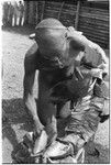 Woman wrapping something in leaves, possibly a piece of uncooked pork