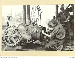 LAE, NE GUINEA. 1944-03-24. QX14541 CRAFTSMAN W. K. BLANK (1), WITH SX4976 CRAFTSMAN O. W. RAGLESS (2), AT WORK ON THE FINAL DRIVE ASSEMBLY OF A CATERPILLAR TRACTOR AT THE 2ND MECHANICAL EQUIPMENT ..