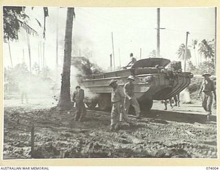 MADANG, NEW GUINEA. 1944-06-17. TROOPS FIGHTING TO EXTINGUISH A FIRE IN A UNITED STATES ARMY AMPHIBIOUS DUKW PARKED NEAR THE AUSTRALIAN MOVEMENT CONTROL OFFICE ON THE BEACH