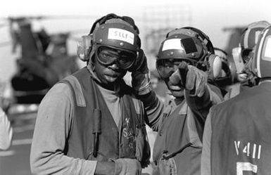 Two flight deck crewmen discuss their duties aboard the amphibious assault ship USS GUAM (LPH 9), during operations off the coast of Beirut, Lebanon