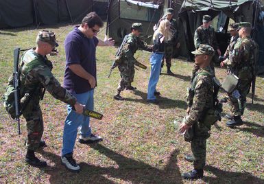 US Marine Corps (USMC) Lance Corporal (LCPL) Alcha Siegrist, right and LCPL Manuel Morin, with the Marine Expeditionary Unit (MEU) Service Support Group (MSSG) 31, search role players for contraband during a simulated Noncombatant Evacuation Operation (NEO) exercise, part of TANDEM THRUST 2003