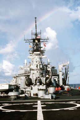 A rainbow provides the backdrop to the superstructure of the USS MISSOURI (BB-63) while the battleship is underway with other ships of its battle group during exercise RIMPAC '90 near Hawaii. Three of the vessel's Mark 7 16-inch/50-caliber guns can be seen in the foreground