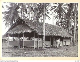 LAE AREA, NEW GUINEA. 1945-08-03. CHAPLAIN W.J. CANTWELL OUTSIDE THE BUSU ROAD ROMAN CATHOLIC CHAPEL AND SANCTUARY