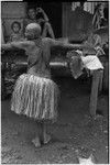 Mortuary ceremony: mourning woman with shaved head, wearing long fiber skirt and beaded necklaces