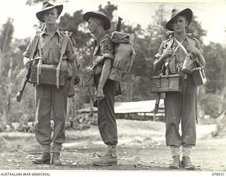 WUNUNG PLANTATION, JACQUINOT BAY, NEW BRITAIN. 1945-02-01. AMMUNITION TRANSPORT. ON THE RIGHT IS DEMONSTRATED THE OLD METHOD OF CARRYING TWO BOXES OF BELT AMMUNITION (250 ROUNDS) WHILE THE CENTRE ..