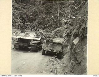 WAU - LAE ROAD, NEW GUINEA, 1944-02-26. CAREFUL DRIVING IS A NECESSITY ON THE NARROW ROAD CUT IN THE FACE OF THE BULOLO VALLEY. THE JEEP MET THE H.D. 7 BULLDOZER OF THE 1ST MECHANICAL EQUIPMENT ..