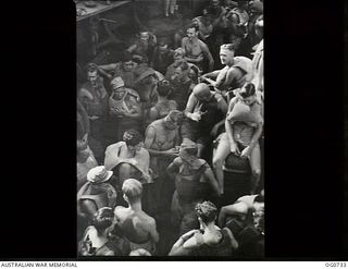 MILNE BAY, PAPUA. C. 1944-02. GROUP OF AIRMEN FROM NO. 75 SQUADRON RAAF ON BOARD SHIP, AT MILNE BAY EN ROUTE TO LAE, FITTING THEIR LIFE JACKETS DURING BOAT DRILL
