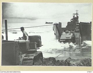 TOKO, BOUGAINVILLE, SOLOMON ISLANDS. 1945-03-20. A 3 TON VEHICLE USED BY THE 11TH FIELD COMPANY, ROYAL AUSTRALIAN ENGINEERS, BEING TOWED ASHORE THROUGH HEAVY SURF FROM THE LCT (LANDING CRAFT TANK) ..