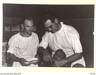 RABAUL, NEW BRITAIN, 1945-10-08. CAPT W.J. STONEY, DENTAL SECTION, 105 CASUALTY CLEARING STATION, PERFORMS A TOOTH EXTRACTION ON JEN D.C. SHARMA, OF THE INDIAN MEDICAL DEPARTMENT, WHO WAS A ..