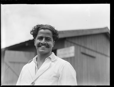 Portrait of a Mr Ahundah outside a wooden building, Nausori Airfield, Fiji