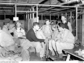 VIVIGANI, GOODENOUGH ISLAND, PAPUA. C. 1943-09. BOMBER CREW OF NO. 100 (BEAUFORT) SQUADRON RAAF AWAITING DEBRIEFING IN STRIP OPERATIONS ROOM AFTER NIGHT RAID ON GASMATA, NEW BRITAIN