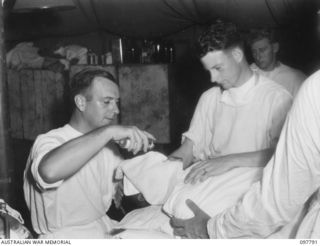 RABAUL, NEW BRITAIN, 1945-10-08. CAPT T.H. THOMSON (1) ASSISTED BY CPL L.W. GROGAN (2), ANAESTHETISED AN INDIAN FORMER PRISONER OF WAR OF THE JAPANESE DURING PREPARATIONS FOR A TOOTH EXTRACTION, AT ..