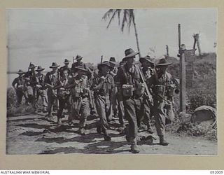 WEWAK POINT, NEW GUINEA, 1945-05-12. 2/4 INFANTRY BATTALION MORTAR MEN PASS SIGNS DENOTING THE BATTLE AREA. THE SIGNS, REMINDERS OF SYDNEY, WERE ON THE ORDERS FOR BATTLE AND WERE ERECTED ..