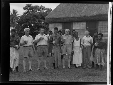A line of Fijians and guests with opened coconuts in their hands at the meke, Vuda village, Fiji