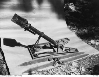 NEW GUINEA. 1943-11-24. JAPANESE SPIGOT MORTAR (ANTI-TANK), SHOWING PROPELLANT CHARGE IN SMALL WHITE BAG RESTING ON THE BASE PLATE. THIS EQUIPMENT HAS BEEN PREPARED FOR DEMONSTRATION PURPOSES BY ..