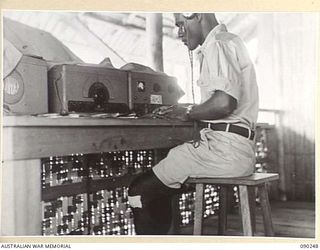 HOMBU HOMBU, NEW GEORGIA ISLAND. 1945-03-28. SERGEANT E. HIELE, WHO IS IN CHARGE OF WIRELESS COMMUNICATIONS, RECEIVING A MESSAGE