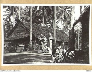 MILNE BAY, NEW GUINEA. 1943-06-26. SX13741 SERGEANT MAINWARING, WAR ARTIST (LEFT), Q46341 DRIVER G. A. COWLEY (CENTRE), AND QX45487 SERGEANT K. E. COLLOM IN FRONT OF THE CAMP COMMANDANT'S OFFICE ..