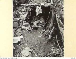 SHAGGY RIDGE, NEW GUINEA. 1944-01-10. QX34526 PRIVATE G.B. ANDREWS OF "A" COMPANY, 2/9TH INFANTRY BATTALION SLEEPING IN HIS DUGOUT ON A SIDE OF THE "PIMPLE"