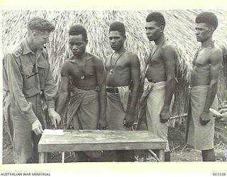 DUMPU, NEW GUINEA. 1944-01-04. AUSTRALIAN AND NEW GUINEA ADMINISTRATION UNIT ASSISTANT DISTRICT OFFICER, PX122 CAPTAIN H. E. HAMILTON SIGNING ON NATIVE LABOURERS BY MEANS OF A THUMB PRINT