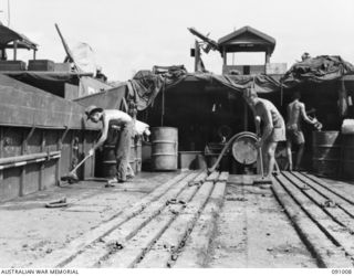 JACQUINOT BAY, NEW BRITAIN. 1945-04-17. MEMBERS OF 41 LANDING CRAFT COMPANY CLEANING MUD FROM THE BARGE AB2027, ACCUMULATED ON THE BARGE DECK DURING THE TRANSPORTATION OF INFANTRYMEN AND TRUCKS. ..