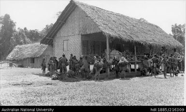 A large number of people gathered around a grass-covered building